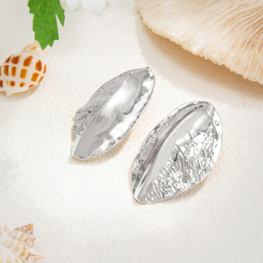 Alba silver-tone statement earrings with raised centre ridges and textured surfaces, shown close up on a white background.